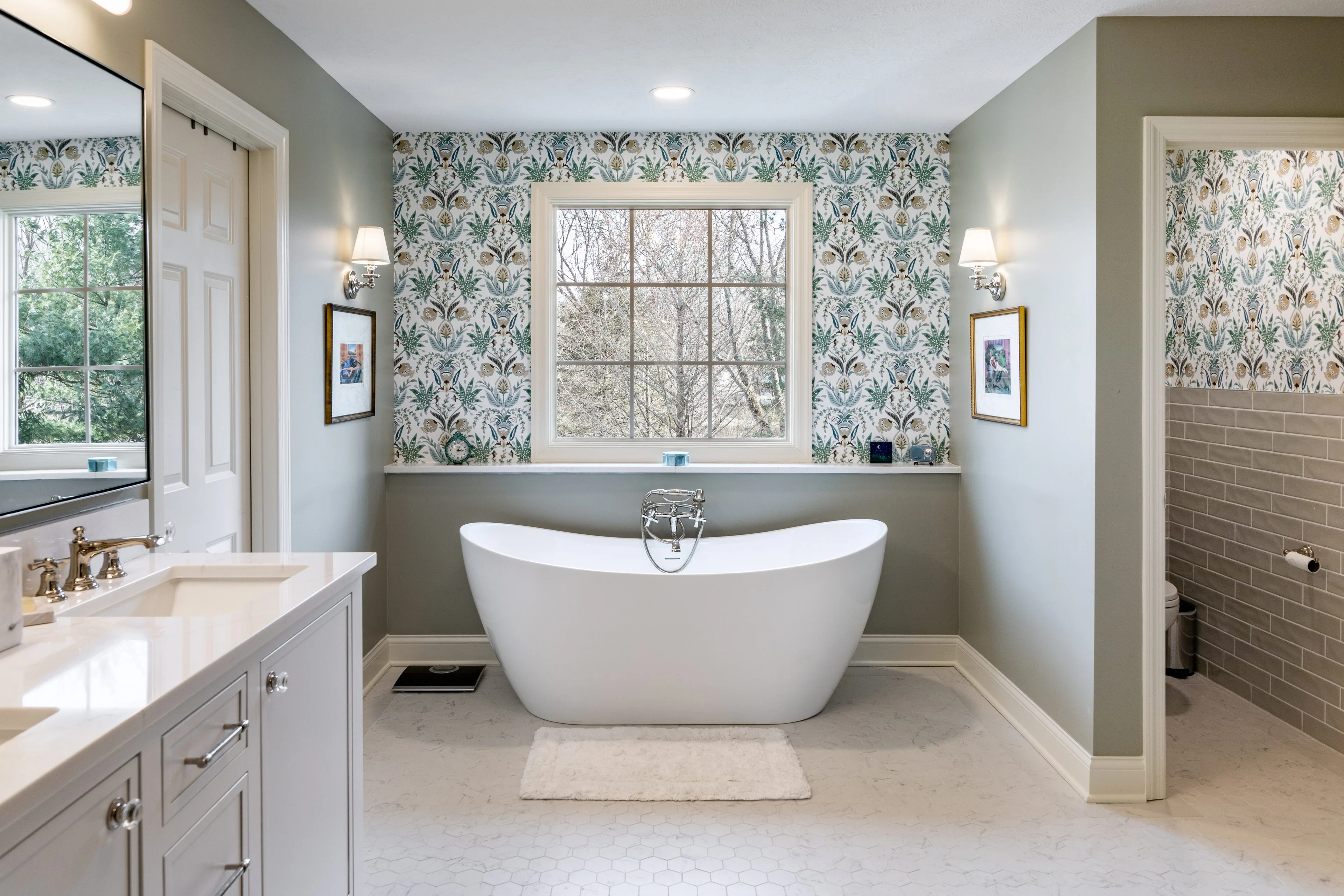 Full bathroom remodel in Blacklick with a freestanding slipper tub beneath a window, botanical wallpaper, polished nickel sconces and a white vanity with quartz top