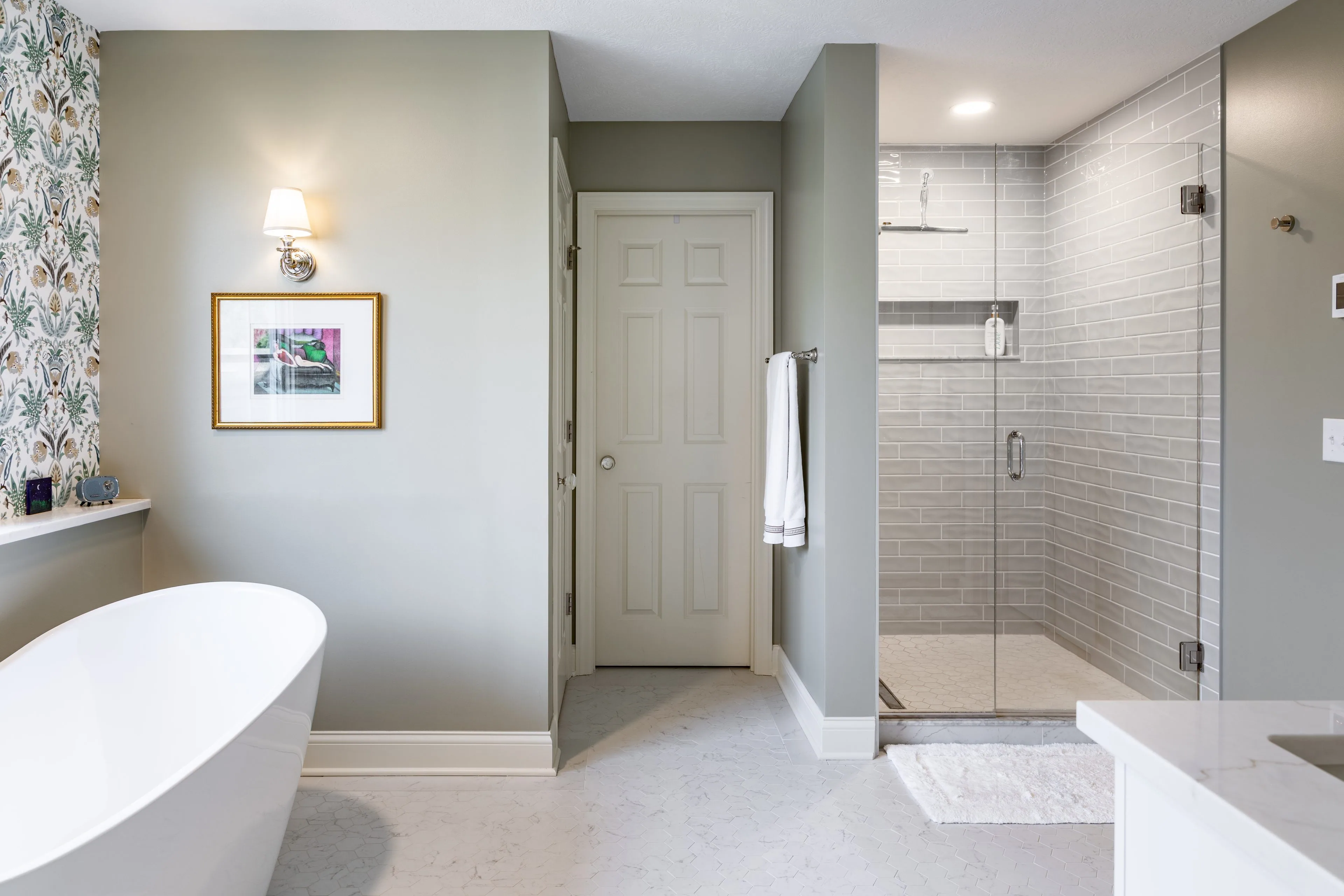 Blacklick primary bathroom with a freestanding tub on the left and a walk-in shower tiled in grey subway with a frameless glass door on the right