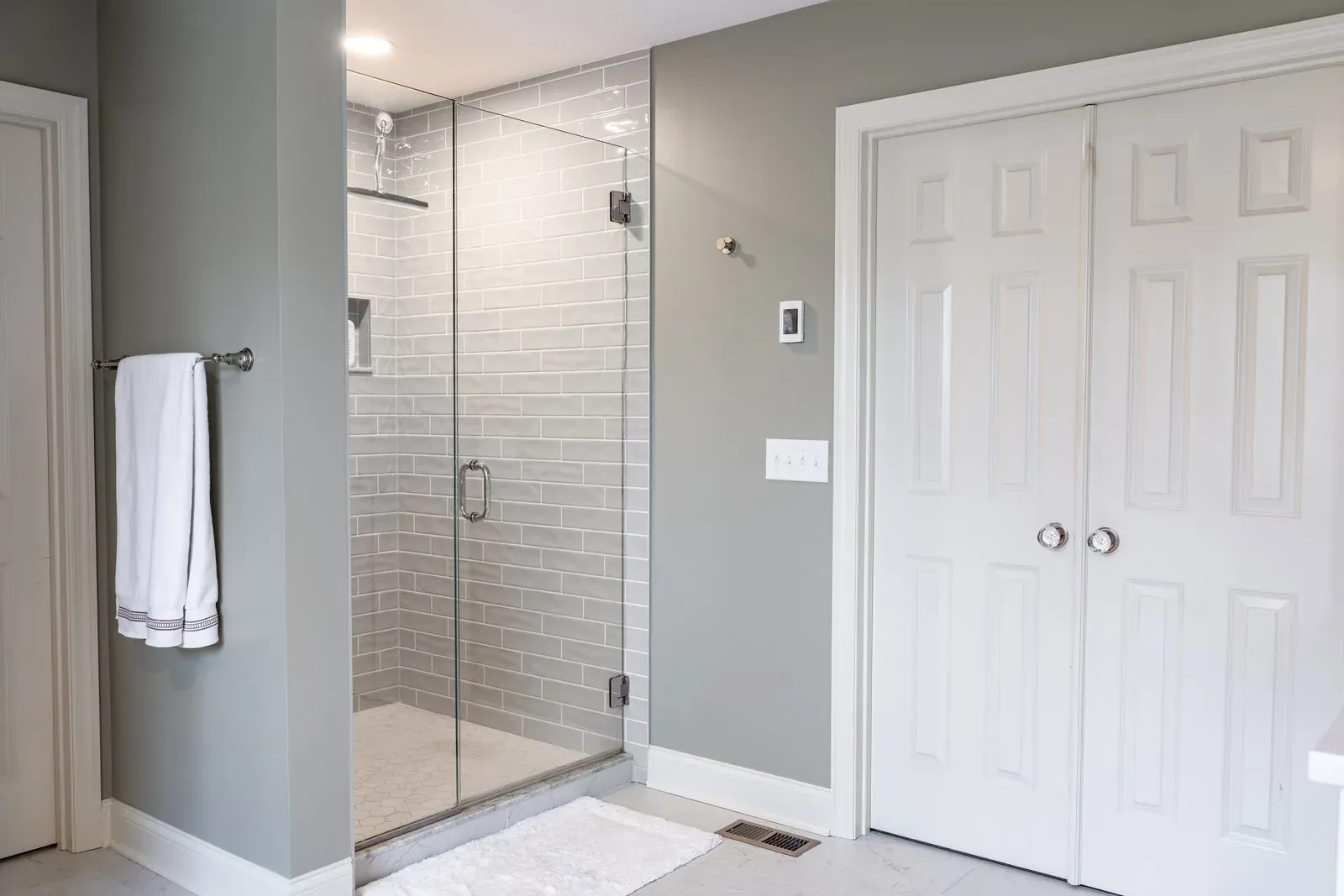 Walk-in shower in a Blacklick bathroom remodel, tiled in grey subway with a frameless glass door and polished nickel fixtures