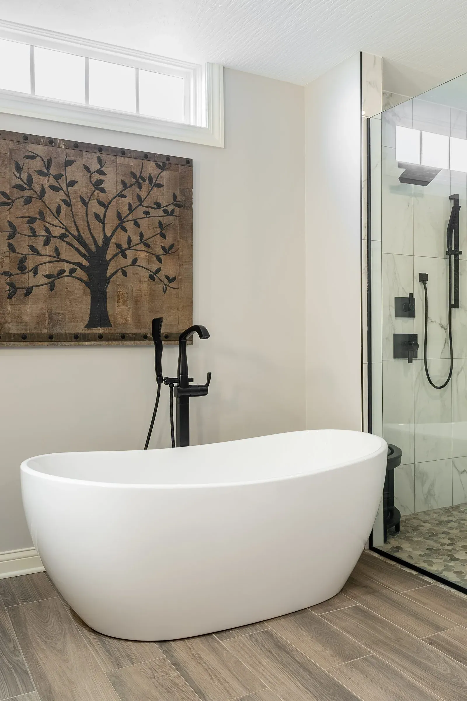 Columbus bathroom remodel with a freestanding soaking tub, matte black floor-mounted filler and a frameless glass walk-in shower over wood-look plank flooring
