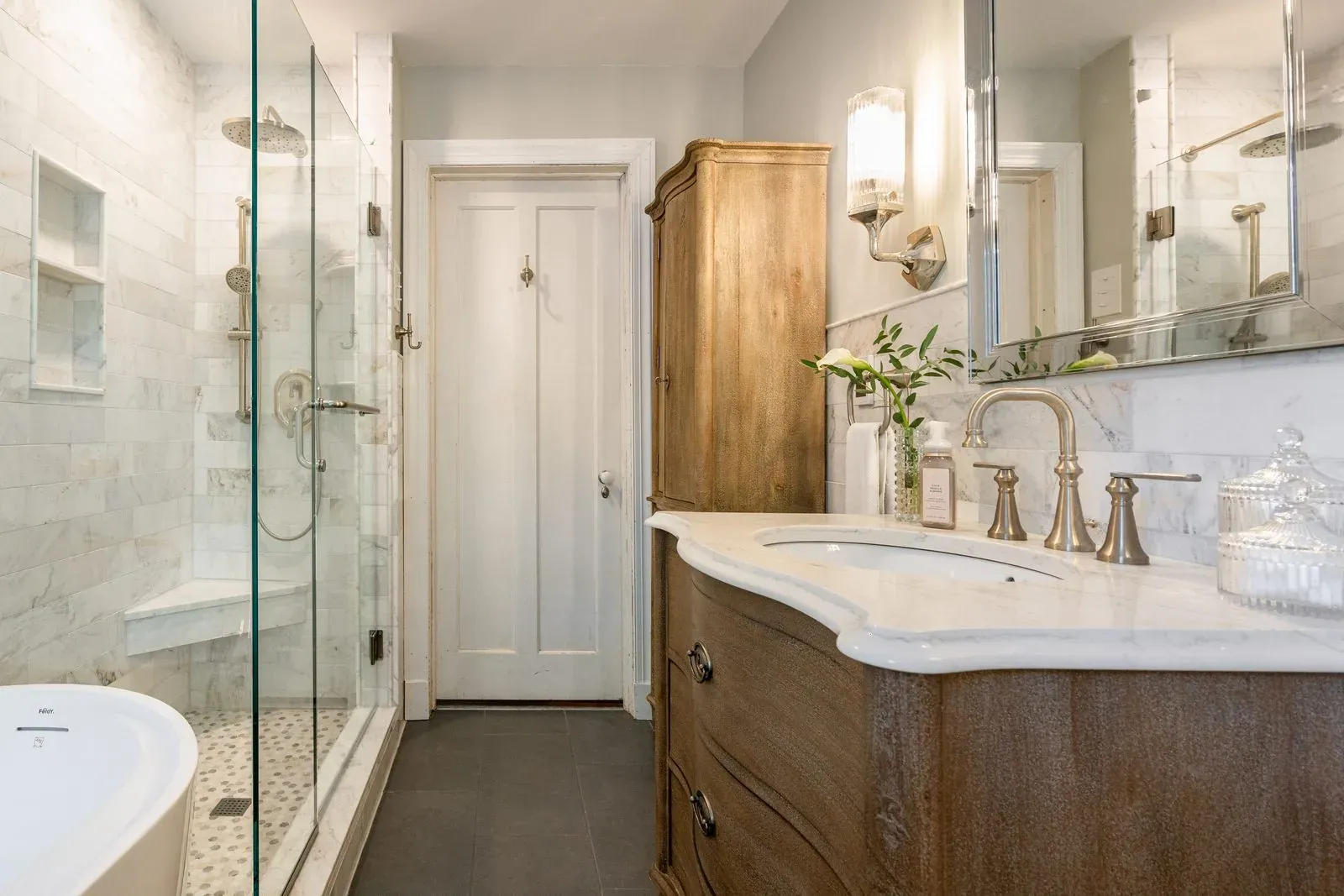 Bathroom remodel with a marble-tiled glass shower, a curved stained wood vanity with a marble top and brushed nickel widespread faucet