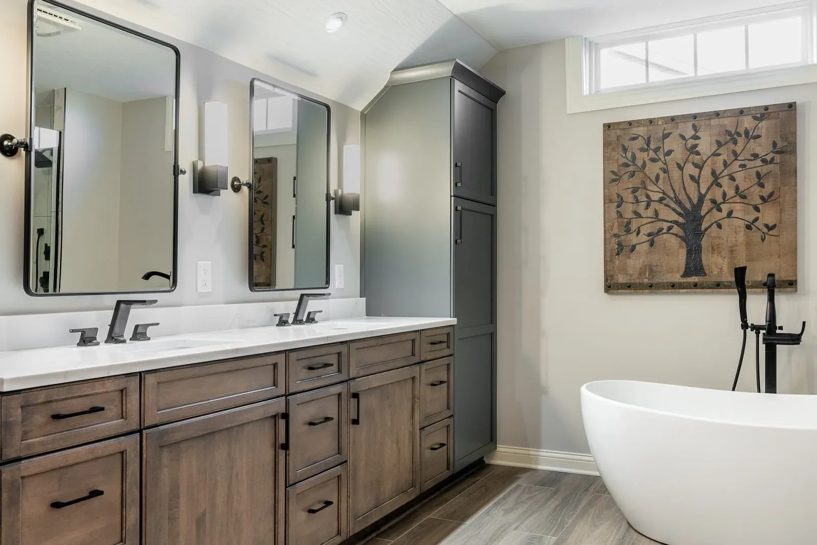 Walnut double vanity with a white quartz top and black framed mirrors, looking across to a freestanding tub on plank flooring