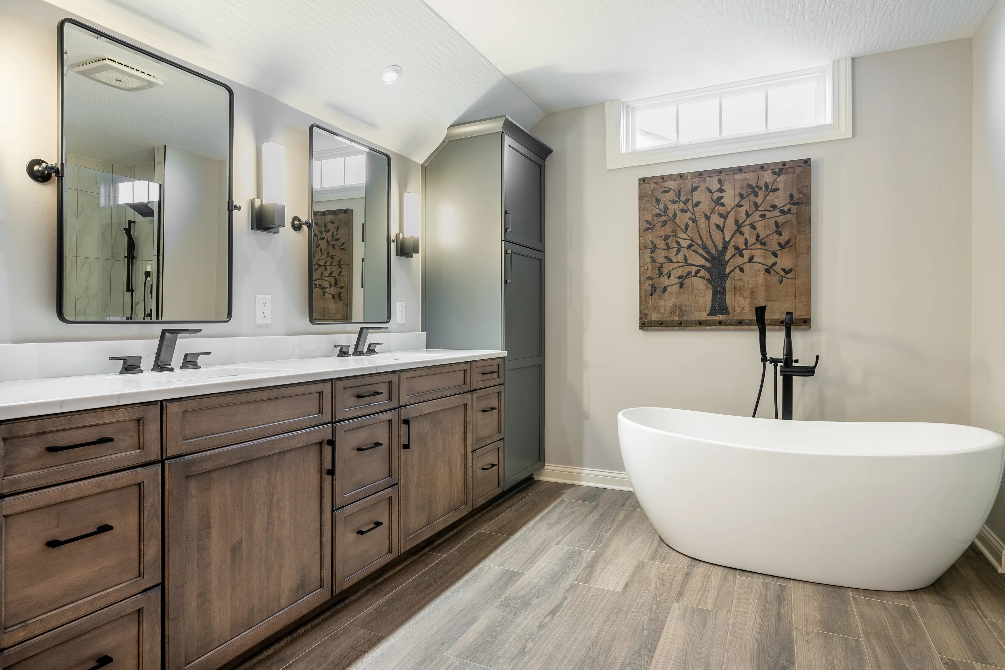 Columbus bathroom remodel with a walnut double vanity, black framed mirrors, quartz countertop and a freestanding tub on wood-look plank flooring